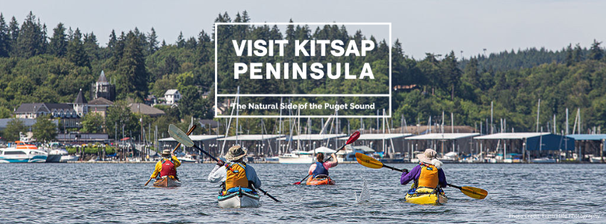 A beautiful moment of kayakers paddling along the water, with the backdrop of a serene waterfront and forested hills. It perfectly captures the essence of Visit Kitsap Peninsula’s branding, highlighting the natural beauty of our region. The text "Visit Kitsap Peninsula: The Natural Side of the Puget Sound" reinforces the connection between outdoor adventure and our unique landscape, surrounded by 371 miles of shoreline.