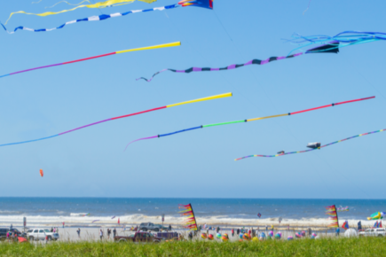 photo of kites being flown above the ocean