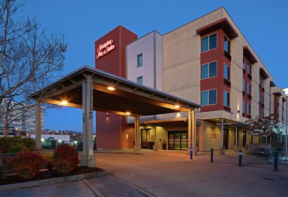 Exterior of Hampton Inn & Suites Bremerton on the waterfront at dusk, showing hotel entrance and covered drop-off area in downtown Bremerton, Washington.