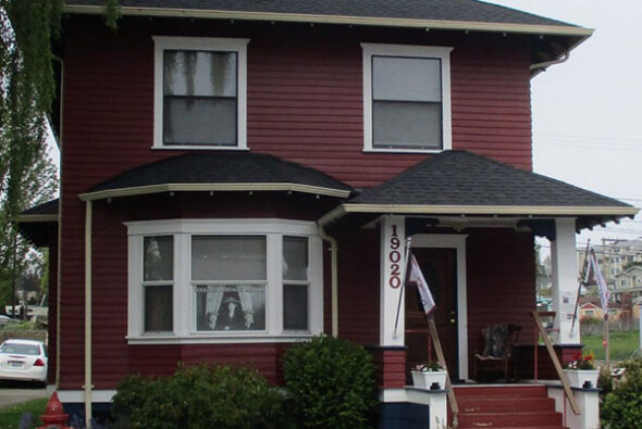 Exterior of the Poulsbo Heritage Museum, a historic red wooden house with white trim and a front porch, located in downtown Poulsbo.