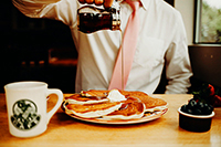 Photo of person pouring syrup on pancakes at The Oak Table Cafe