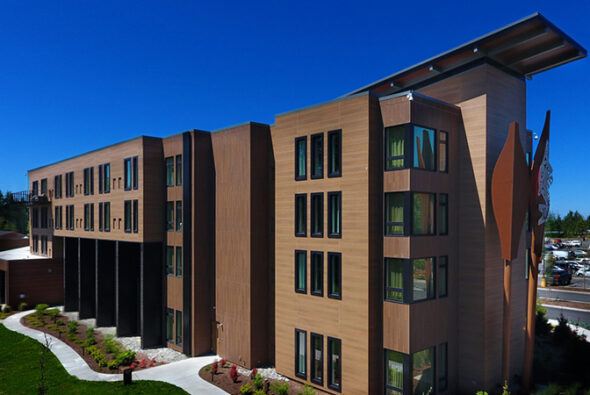 Exterior of The Point Casino and Hotel in Kingston, Washington, showing modern architecture surrounded by landscaped grounds and clear blue sky.
