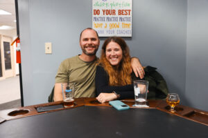 Emma and her husband smiling and sitting together at Ashley's Pub in Bremerton, WA, enjoying drinks after a fun day of exploring the city.