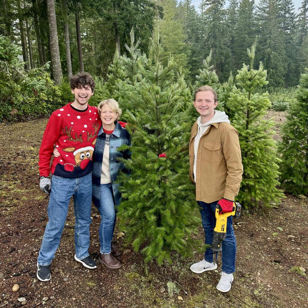 Kitsap County Commissioner Katie Walters and her two sons smile beside their freshly cut Christmas tree at Hubert’s Tree Farm in Seabeck, surrounded by evergreens and holiday cheer.