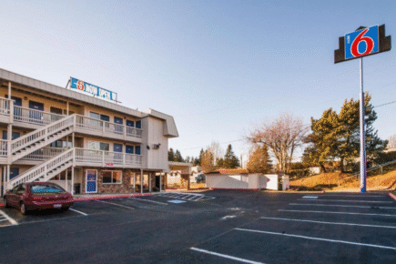 Exterior of Motel 6 Bremerton with parking lot, two-story motel layout, and clear sky in Bremerton, Washington.